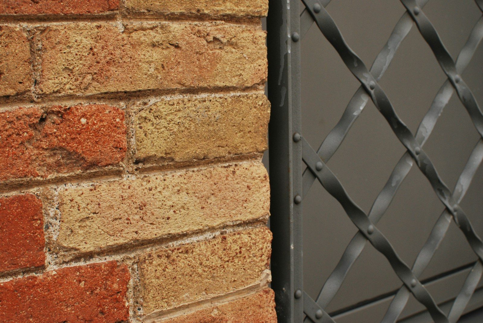 A close up of a brick wall with a metal gate