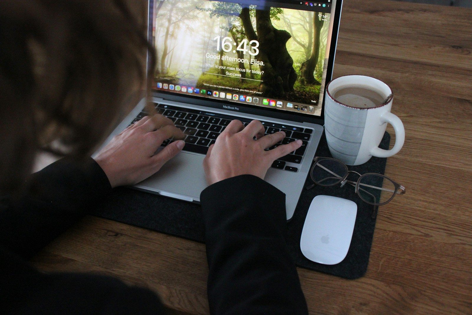 person using macbook pro on brown wooden table