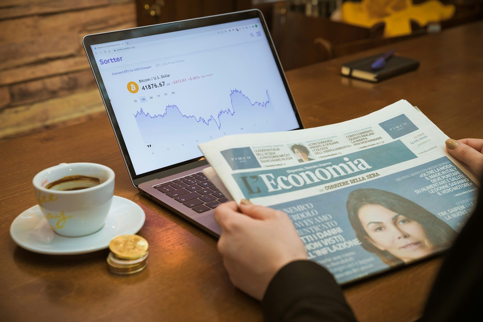 a person reading a newspaper next to a cup of coffee